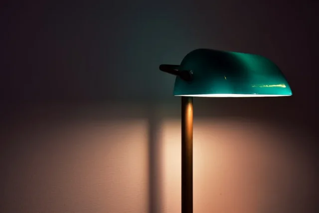 Vintage teal bankers lamp casting warm glow on wal