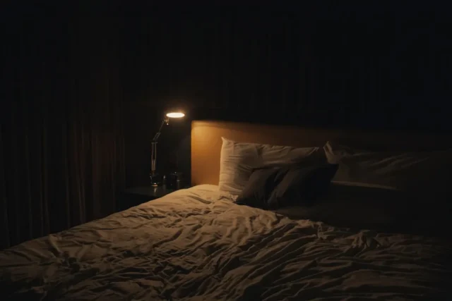 Dark bedroom at night with single small desk lamp