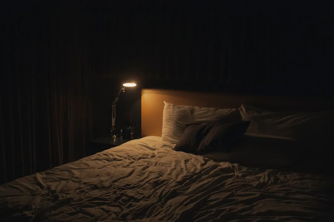 Dark bedroom at night with single small desk lamp