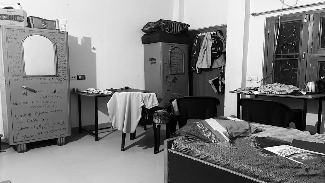 Cluttered student dorm room with mismatched furnit