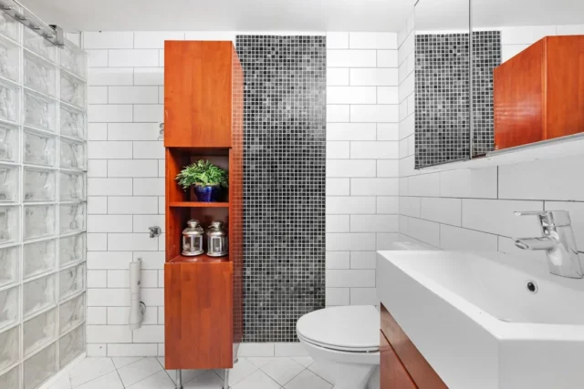 Small bathroom with tall wooden storage cabinet, o