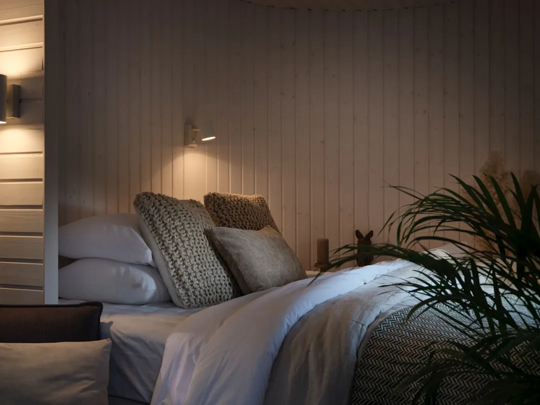 Cozy small bedroom with layered pillows, warm wall