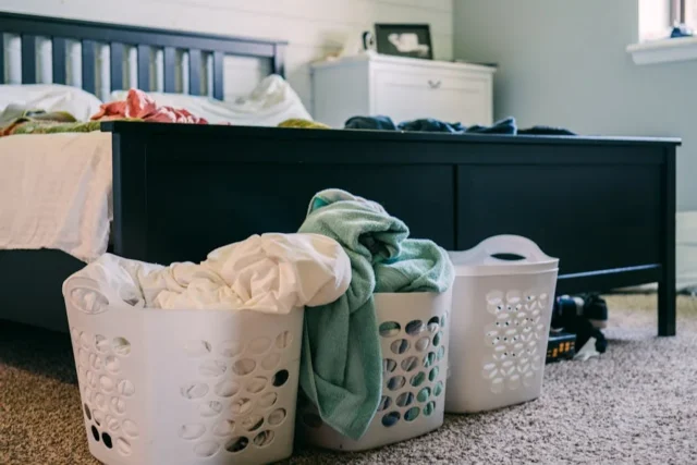 Three white laundry baskets filled with clothes on