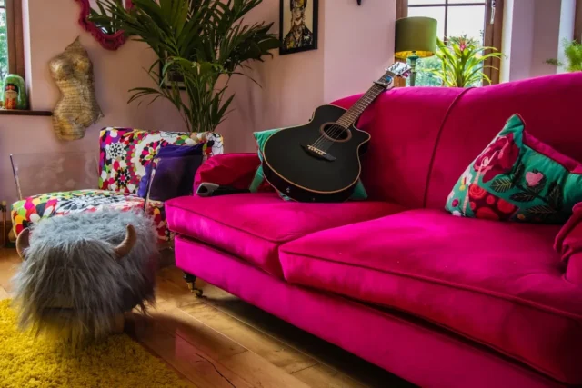 Bold fuchsia velvet sofa with colorful cushions in
