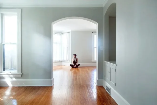 Young woman sitting cross-legged alone on hardwood