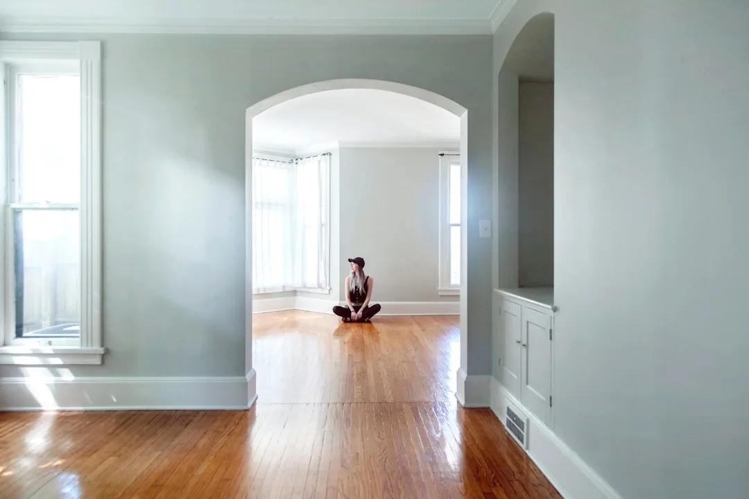 Young woman sitting cross-legged alone on hardwood