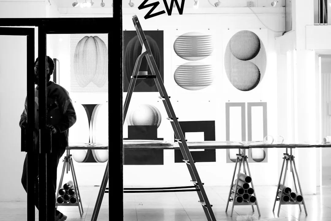 Black and white art gallery with geometric prints, ladder, and silhouetted figure illustrating visual proportion and des