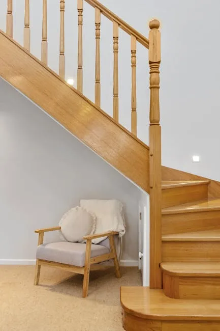 Small armchair tucked under wooden staircase showi
