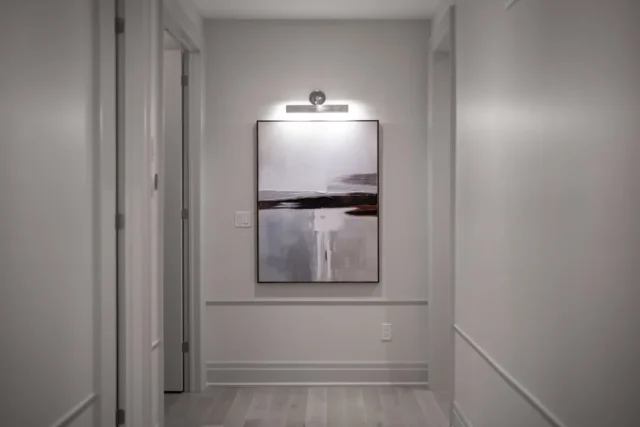 Dark hallway with picture light illuminating abstr