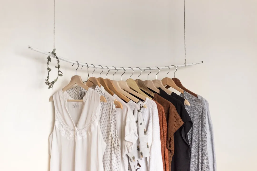 Clothes hanging on a suspended wooden branch rack with wooden hangers against a white wall