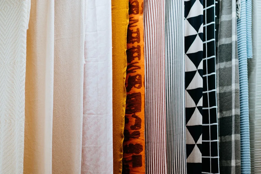 Multiple fabric swatches hanging side by side showing various patterns, textures and colors for interior decorating sele