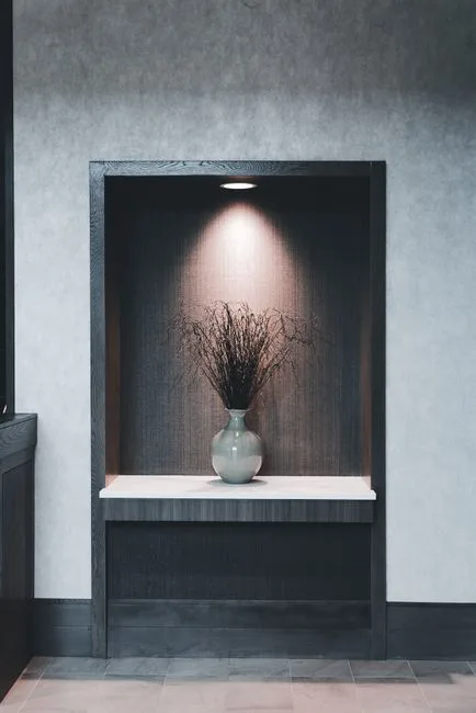 Recessed wall alcove niche with dark wood frame, built-in shelf, and spotlight showcasing depth from wall cavity
