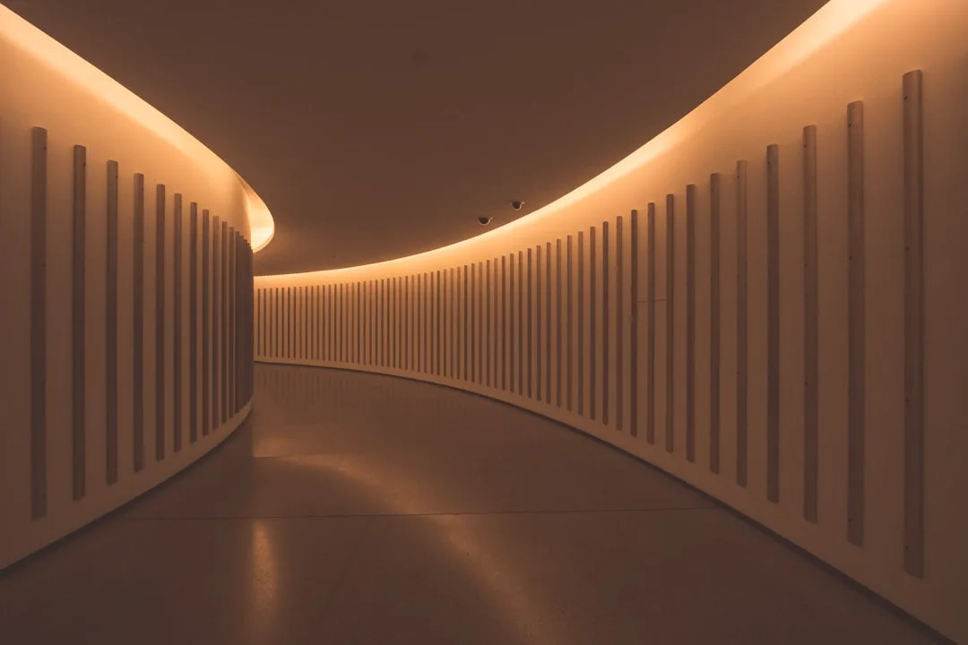 Curved architectural corridor with warm ambient LED cove lighting creating elegant atmospheric glow along the walls