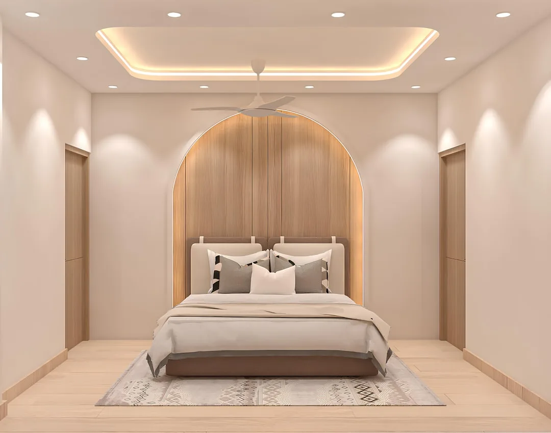 Modern bedroom with layered lighting design featuring LED cove ceiling, recessed spotlights and warm wood arch headboard