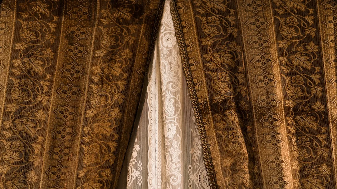 Ornate gold and brown brocade curtains with lace lining showing fabric texture and drape detail
