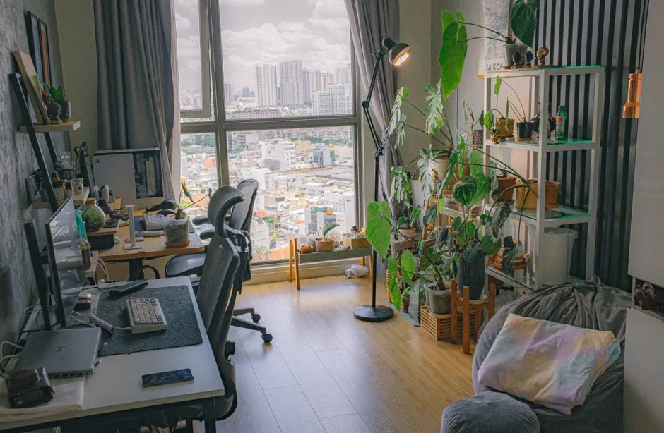 Home office workspace with dual-purpose room setup featuring desk, ergonomic chair, plants, and couch in a high-rise apa