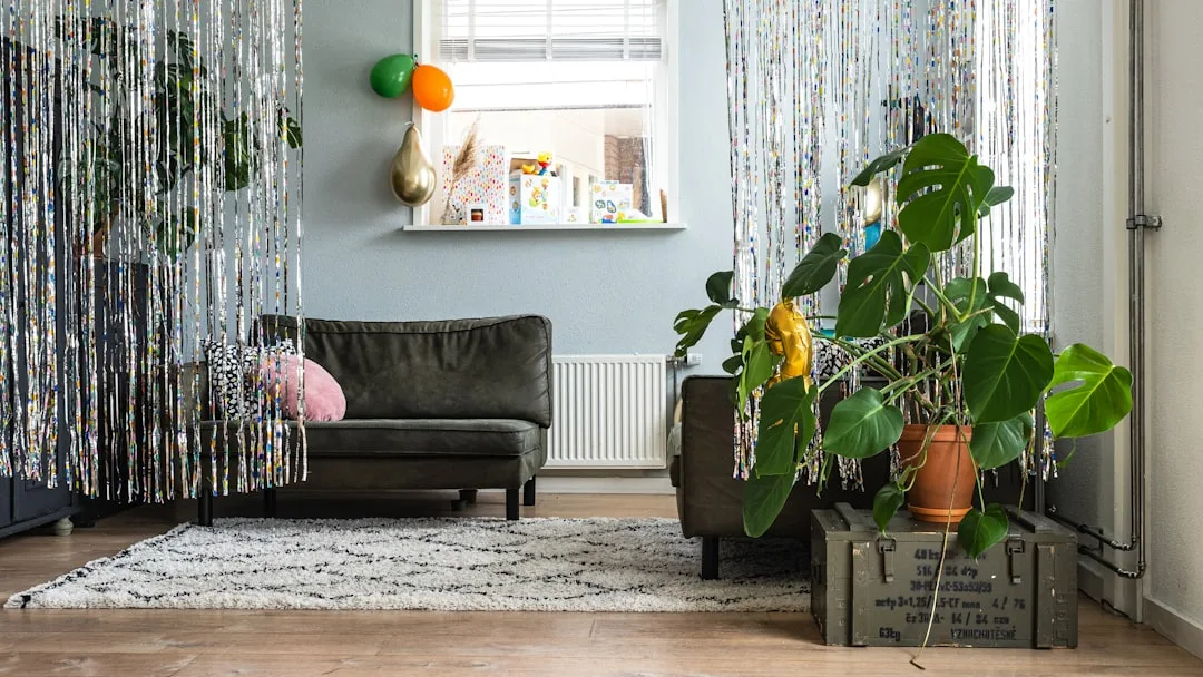 Living room with shiny tinsel curtain panels used as decorative room dividers alongside a dark leather sofa