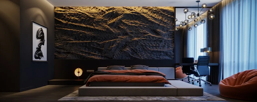 Luxury dark bedroom with rust-orange bedding, textured stone feature wall, and modern sputnik chandelier