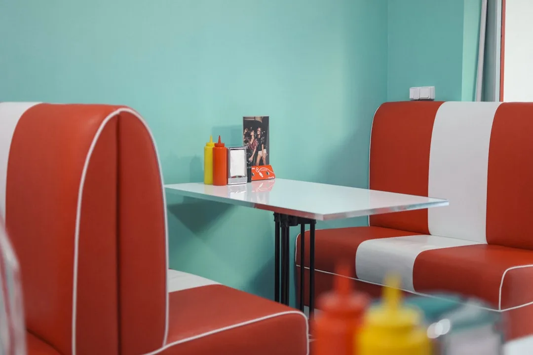 Retro diner-style booth nook with red and white vinyl bench seats and white table with condiments