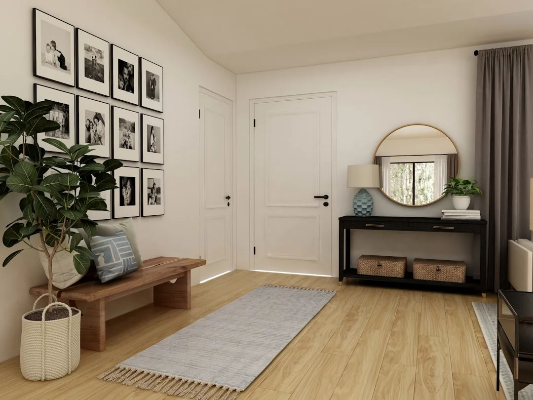 Minimalist apartment entryway with wooden bench, gallery wall, round mirror, and console table on light hardwood floor