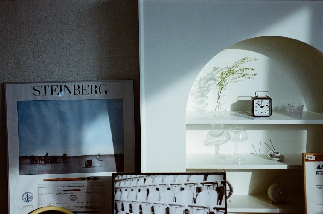 White shelf niche with incense holder, glass vase with dried stems, and small clock in a minimalist living space