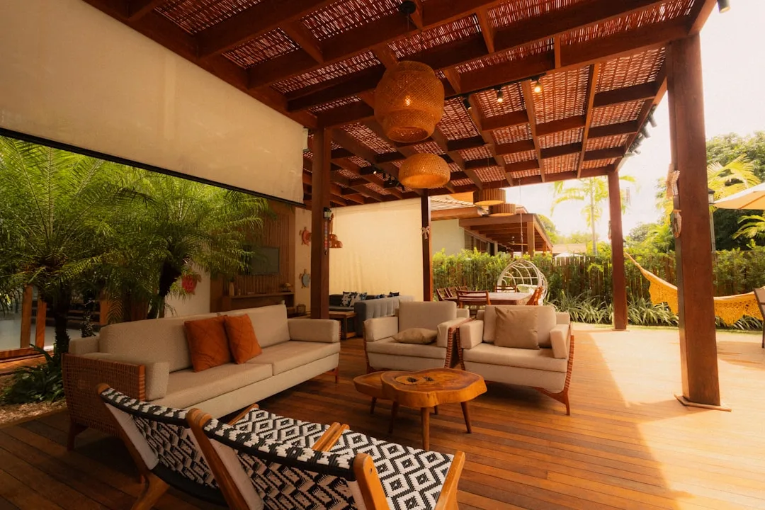 Sustainable hardwood deck with woven pendant lights and natural wood furniture in a tropical outdoor living space