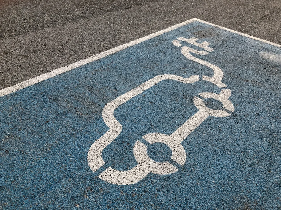 Blue electric vehicle charging parking zone with white EV car and plug symbol painted on asphalt