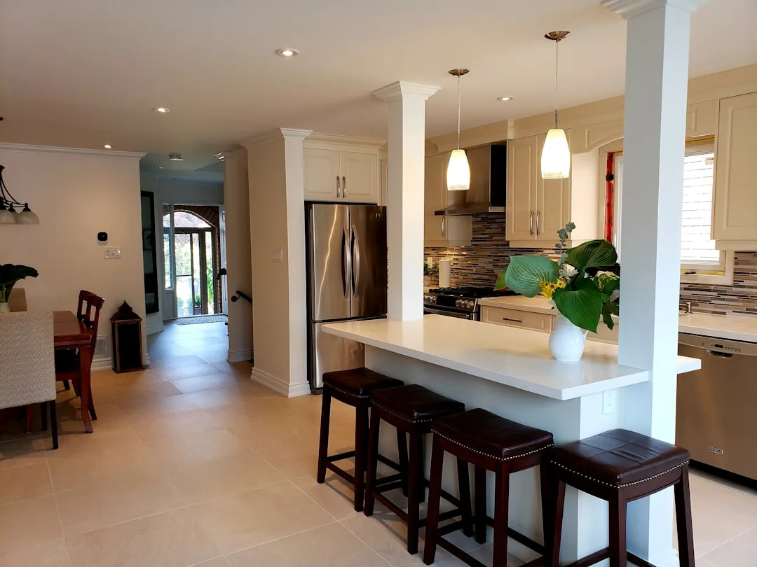 Open-concept kitchen with white island bar, leather bar stools, and adjacent dining nook in modern home