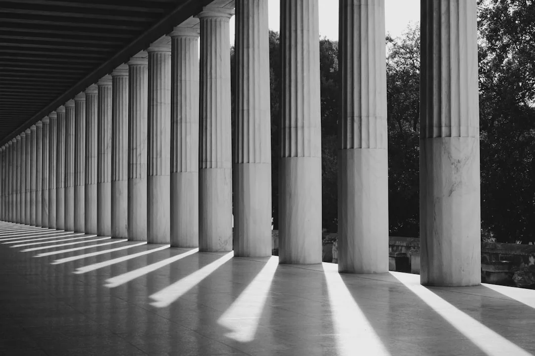 Classical fluted marble columns in a colonnade casting dramatic shadows, illustrating architectural column design as thr