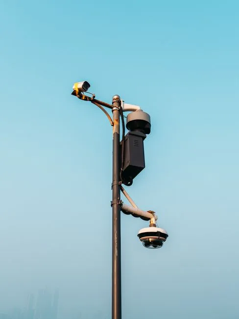 Smart outdoor surveillance pole with multiple CCTV cameras and dome security cameras against clear blue sky