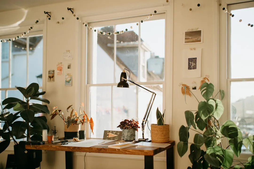 Home office desk with adjustable black lamp positioned in front of window for optimal lighting during video calls