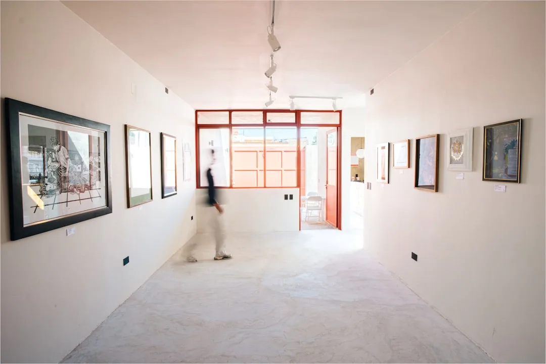 Modern art gallery with white walls displaying framed artwork in a minimalist corridor layout