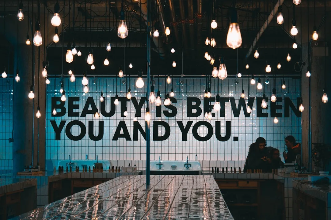 Dozens of Edison bulbs hanging from ceiling in a beauty store with tiled wall and inspirational quote signage