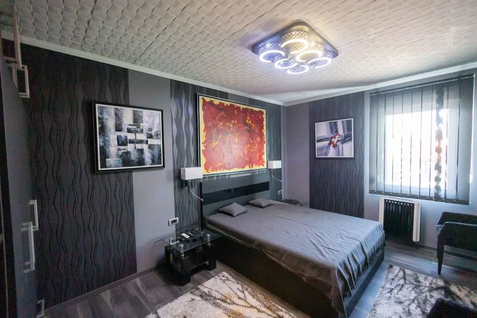 Modern bedroom with low ceiling featuring decorative textured tiles and multi-ring LED flush mount ceiling light fixture