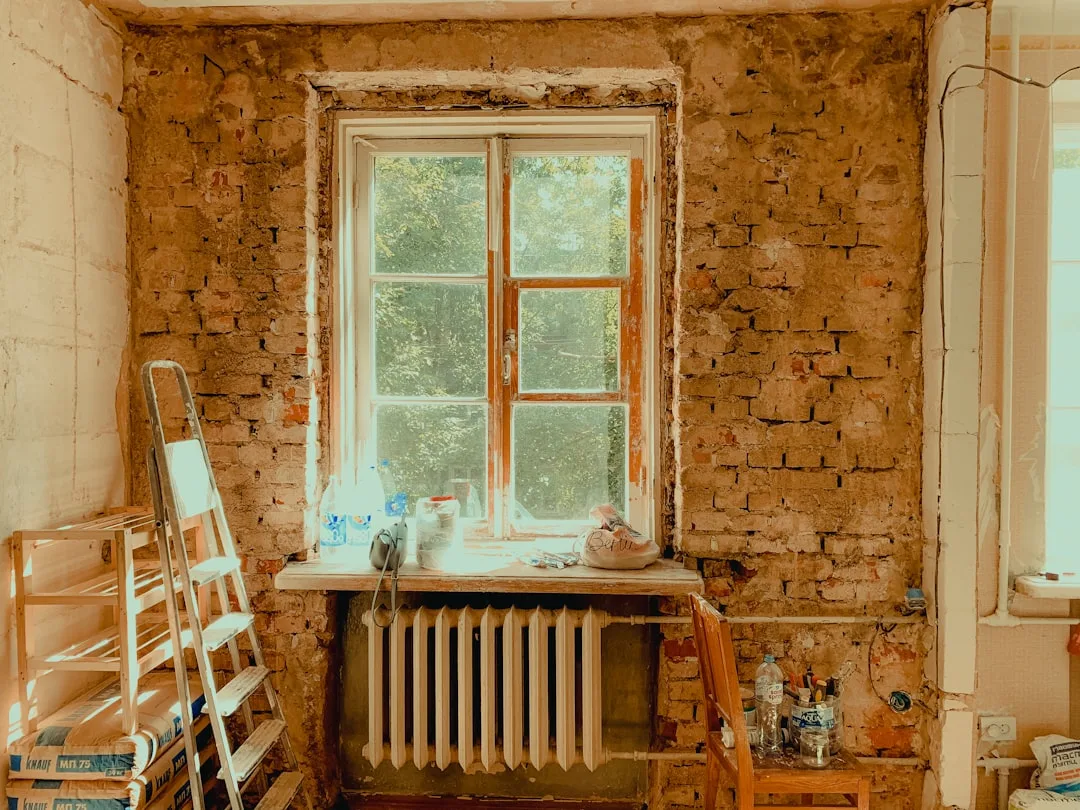 Room under renovation with exposed brick walls, ladder, radiator, and construction materials for tax deduction article