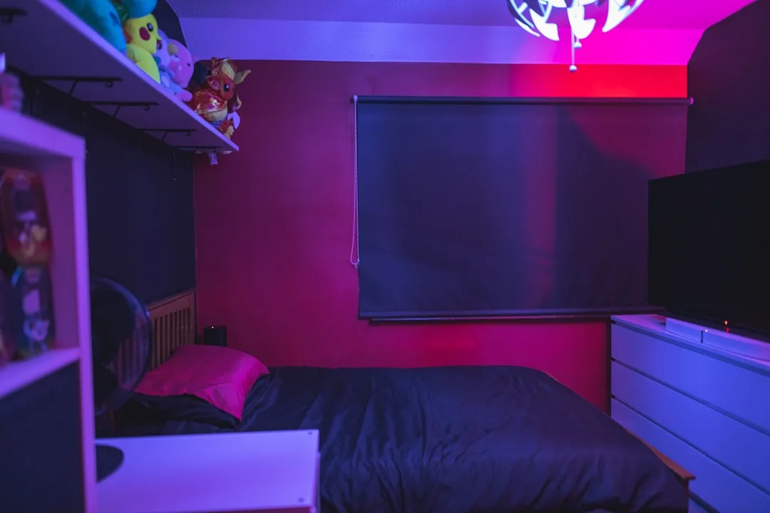 Bedroom with warm red and purple LED strip lighting creating contrasting color temperatures against dark walls
