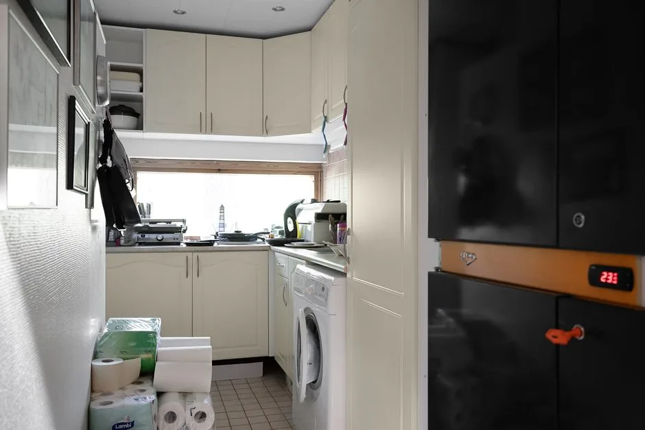 Small galley kitchen with washing machine under counter, white cabinets, and compact laundry storage layout