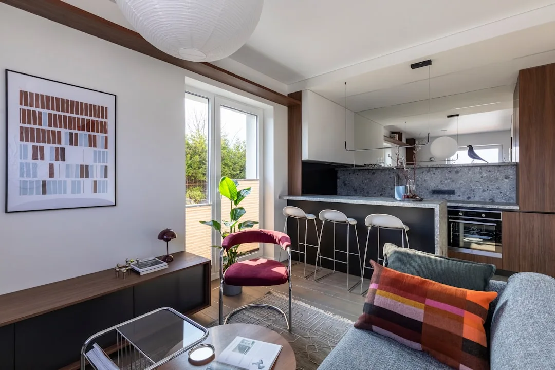 Modern open-plan living room with kitchen bar seating four stools and integrated dining area in compact apartment
