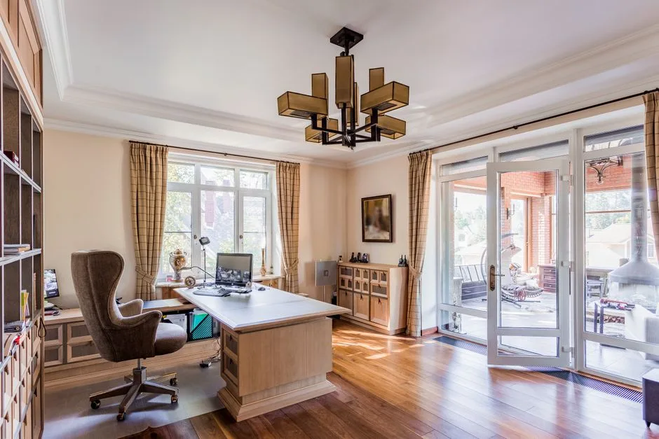 Home office desk positioned near large windows showing natural light direction impact on monitor visibility