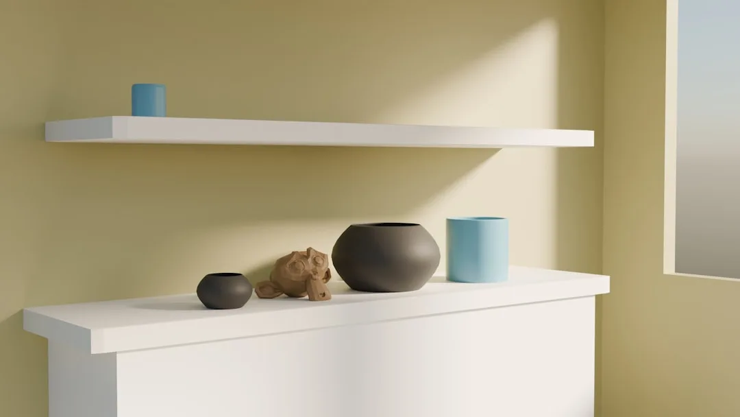 White floating shelf above cabinet displaying dark ceramic bowls, wooden figurine, and blue cylindrical vases in minimal