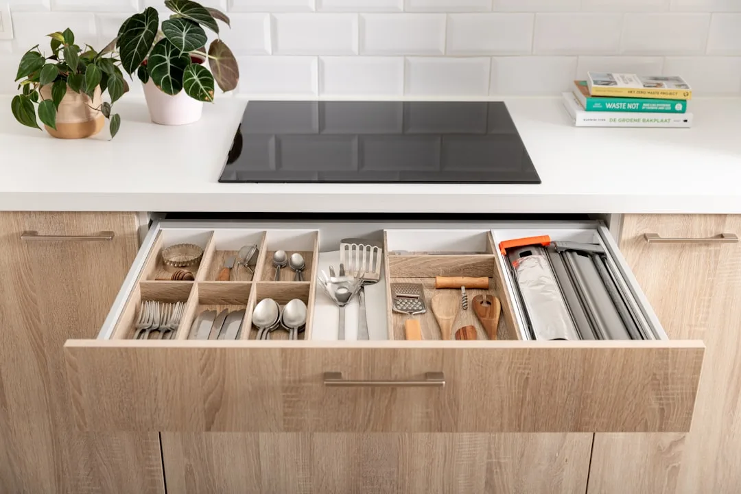 Organized kitchen drawer with cutlery divider, wooden utensils, and cooking tools neatly arranged in compartments