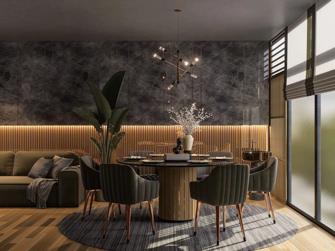 Round dining table with 6 velvet chairs in a small modern dining room with dark marble accent wall