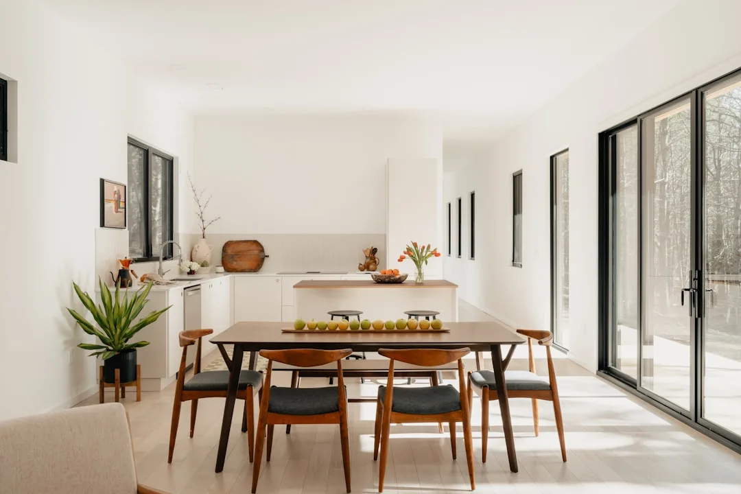 Mid-century modern dining table with chairs in open-plan studio apartment sharing space with white kitchen