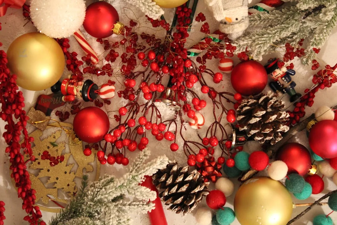 Christmas ornaments, red berries, pine cones, gold and red baubles spread out for holiday decorating
