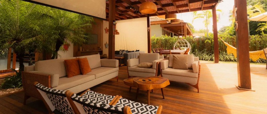 Covered outdoor living space with pergola, wood deck, beige sofas and tropical garden — high-ROI outdoor improvement 202