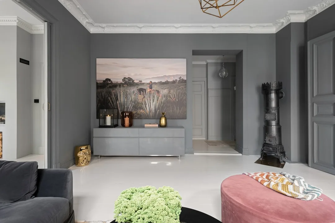 Modern living room with true neutral gray walls, white crown molding, gray sideboard, and eclectic decor accents