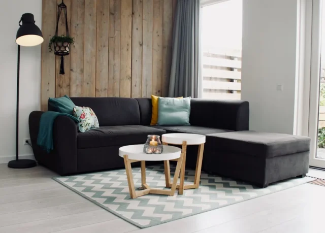 Dark gray sectional sofa on a chevron 9x12 rug wit