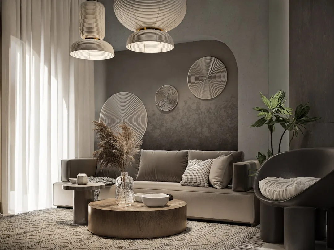 Dimmed pendant lights over modern living room with gray sofa, round wood coffee table, and warm ambient lighting