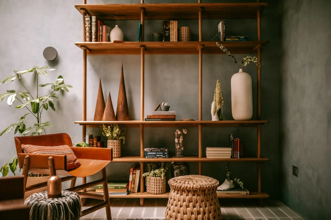 Styled open wooden bookshelf with vases, books, plants and decorative objects in a modern bohemian living room