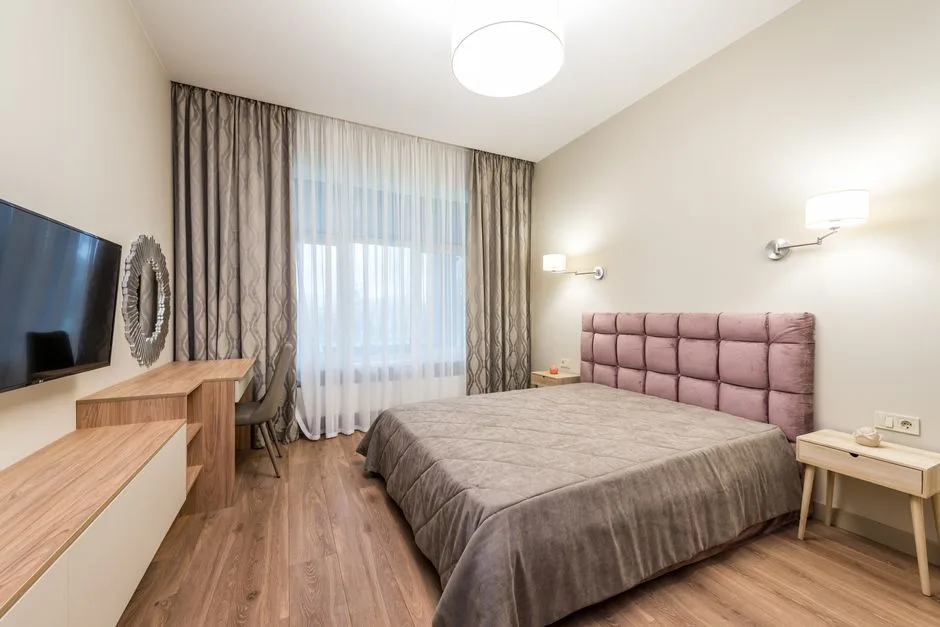 Modern 12x12 bedroom with wall sconces, ceiling light, and soft white walls showing layered lighting design